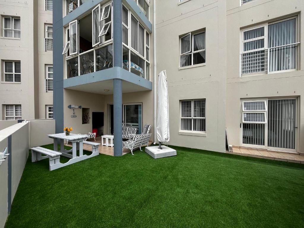 a patio with a green lawn in front of a building at La Palma Villa 8 in Mossel Bay