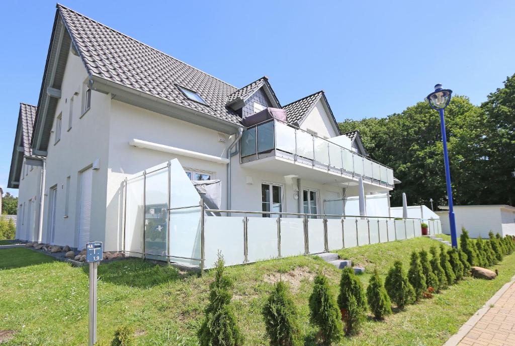 a white house with a fence in front of it at Haus Sonne - Whg 08 in Thiessow