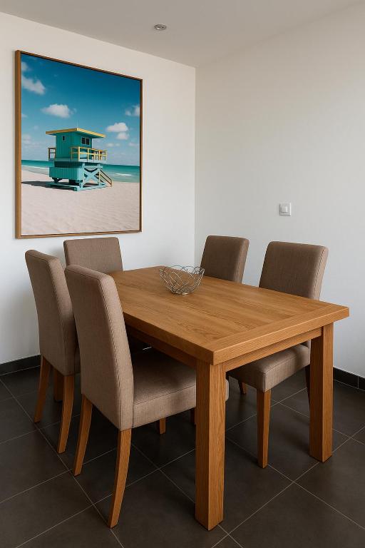 a dining room table with chairs and a picture of a beach at Holidays in Sainte-Maxime