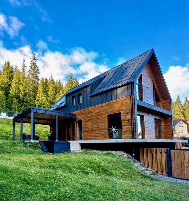 a wooden house with a black roof on a green field at Cabana Nord Side in Muntele Cacovei