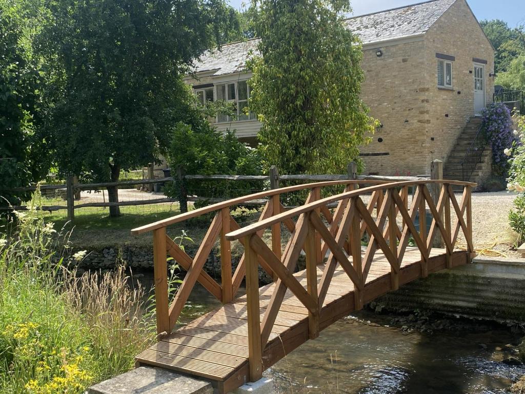 a wooden bridge over a stream in front of a house at The Annexe, Cleveley Mill in Chipping Norton