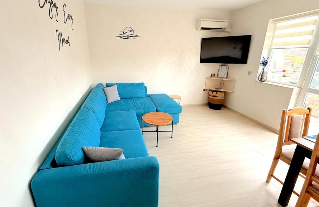 a blue couch in a living room with a tv at Moni Sunset Apartment Balchik in Balchik