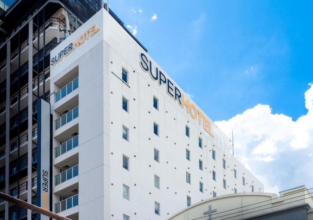 a white building with a sign on top of it at Super Hotel Namba Nipponbashi in Osaka