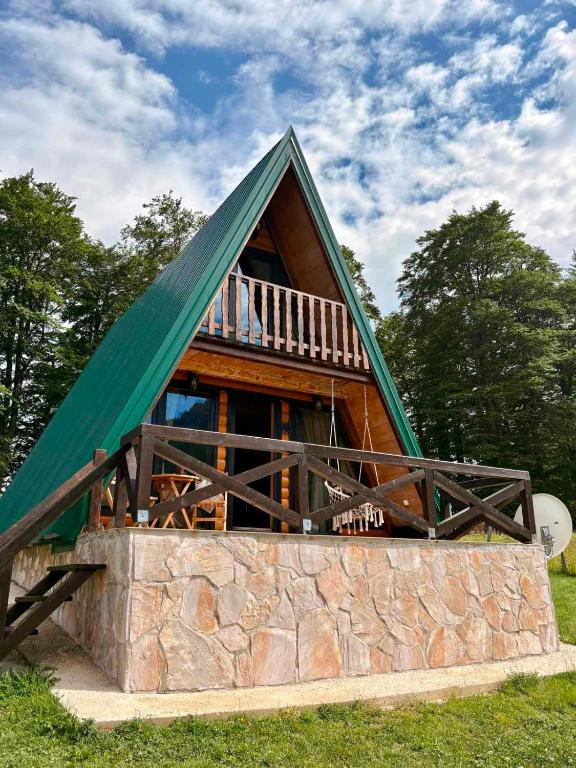 a house with a green roof on top of a stone wall at Vikendica Aleksandra in Žabljak