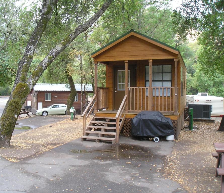 Cabaña de madera pequeña con escalera en un parque en Russian River Camping Resort One-Bedroom Cabin 2, en Cloverdale