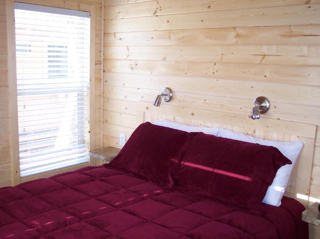 a bedroom with a red bed with a wooden wall at Snowflower Camping Resort Wheelchair Accessible Cottage 8 in Emigrant Gap