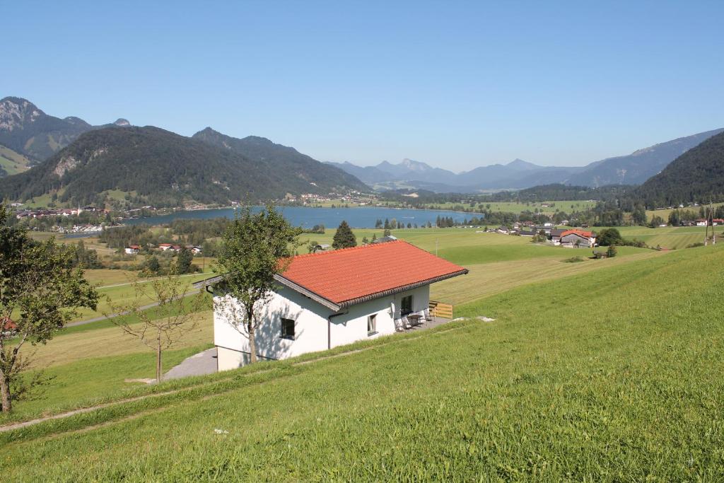 a small white building with a red roof on a hill at Chalet Strobl in Walchsee