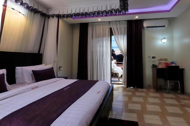 a bedroom with a large bed and a room with a table at Rubax motel mbarara in Mbarara