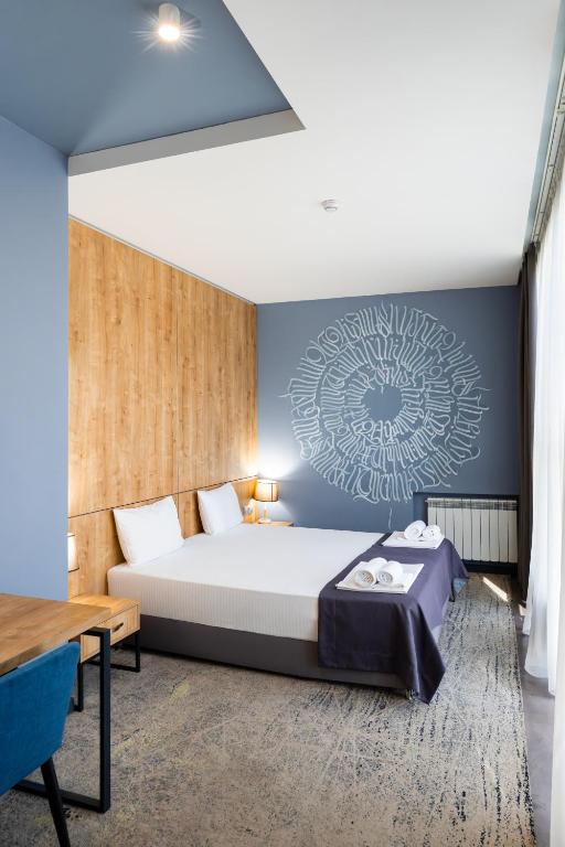ein Schlafzimmer mit einem Bett und einer blauen Wand in der Unterkunft Alpha by Horizon Hotels, Yerevan in Yerevan