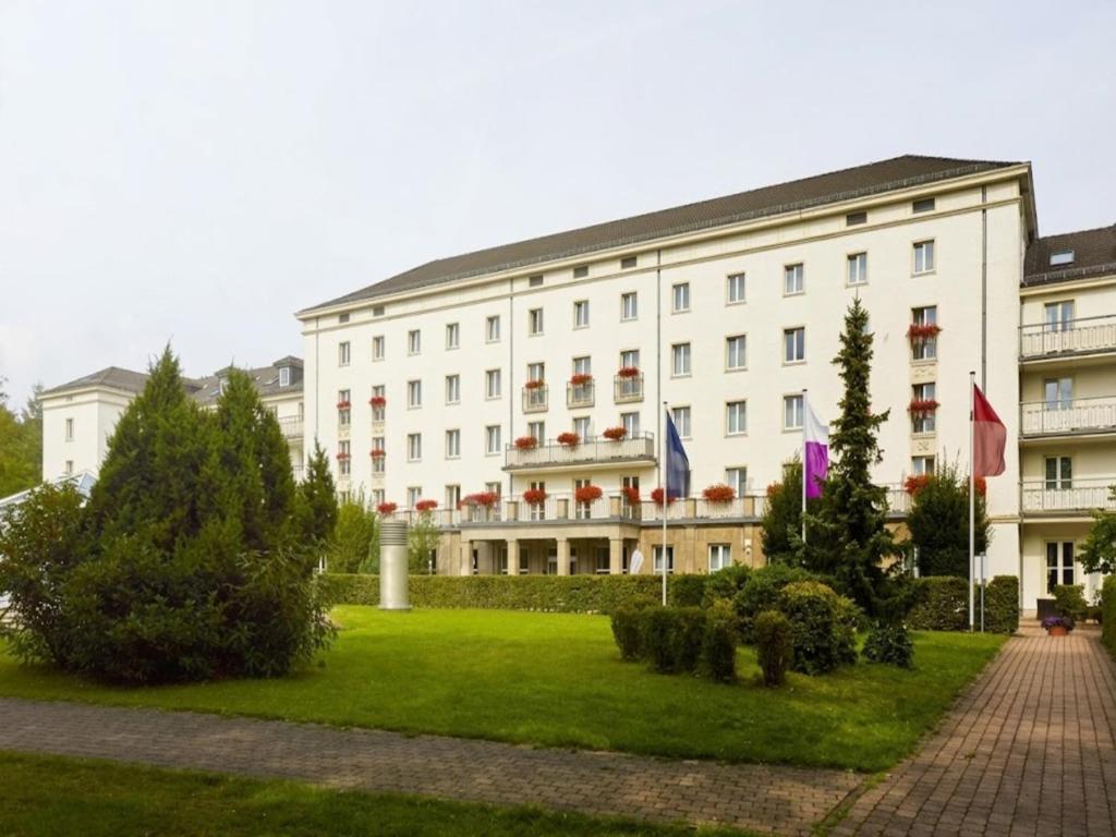 a large white building with flags in front of it at Sunday Hotel Friedrichroda & SPA in Friedrichroda