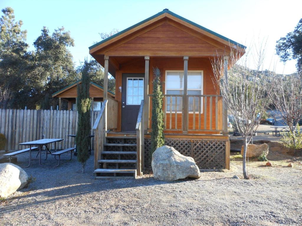 Cabaña de madera pequeña con banco y mesa en Oakzanita Springs Camping Resort Cabin 1 en Descanso