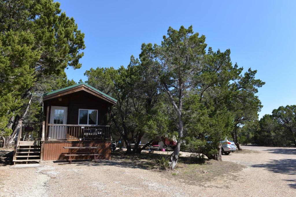 a small cabin in the middle of some trees at Lake Whitney Camping Resort Cabin 1 in Whitney