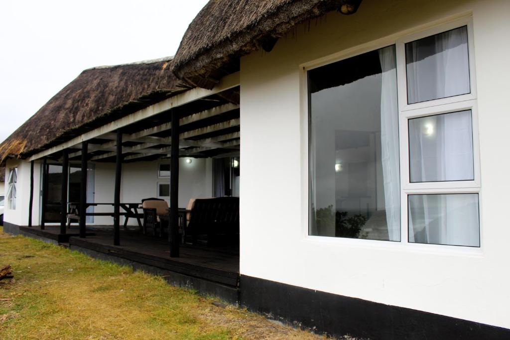 a white house with a thatched roof at Hole in the Wall - Unit H1 in KuGqangushe