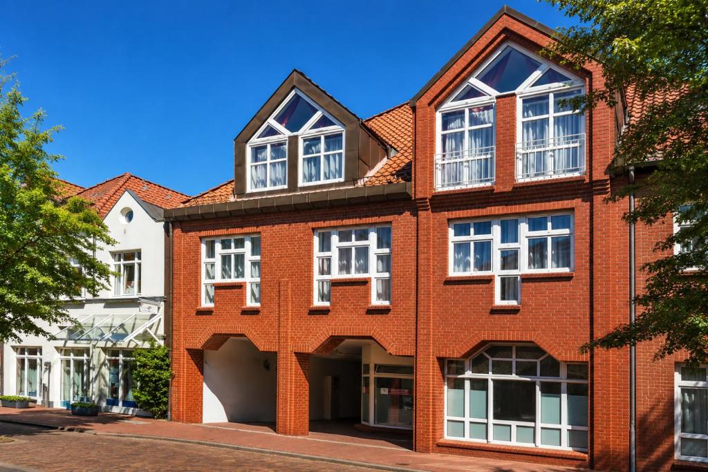 a red brick building with white windows on a street at Sunday Hotel Stade Herzog Widukind in Stade