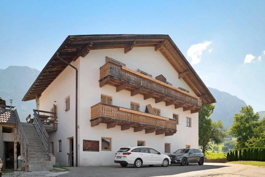 two cars parked in front of a building with wooden balconies at Gatterpunerhof in Vols am Schlern