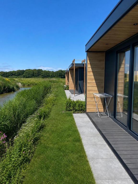 a house with a deck next to a river at Waddenlodge Premium in Harlingen