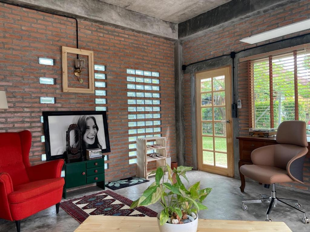 a living room with a brick wall and a tv at Quiet Page CNX in Ban Phae Buak Ha