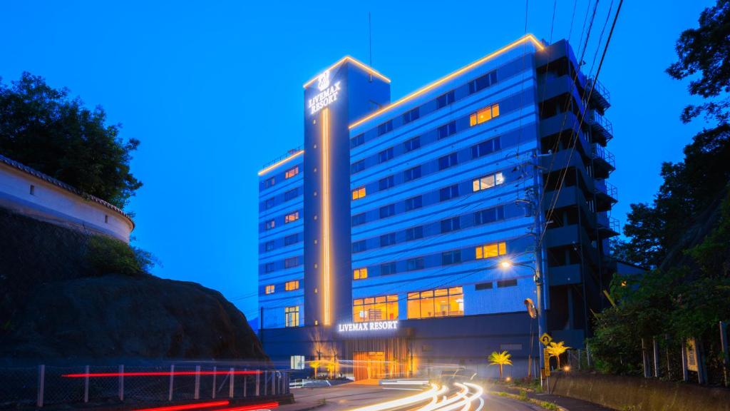 a tall blue building with lights on it at night at Livemax Resort Mihara Onsen Seafront in Mihara