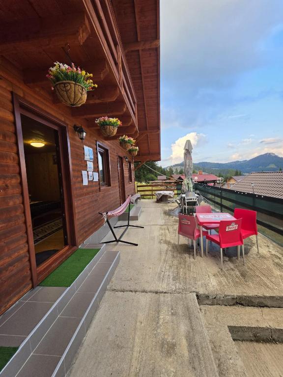 a patio with red tables and chairs on a building at Cabanutele Geo in Lacu Rosu