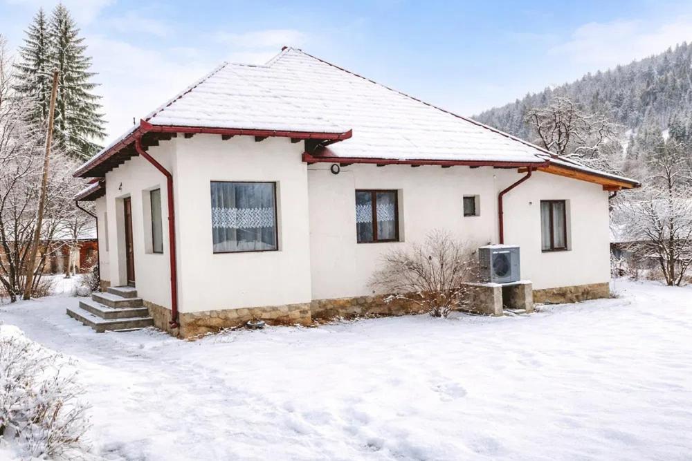 a small white house with snow on the ground at Matei tiny house in Grinţieşu Mic