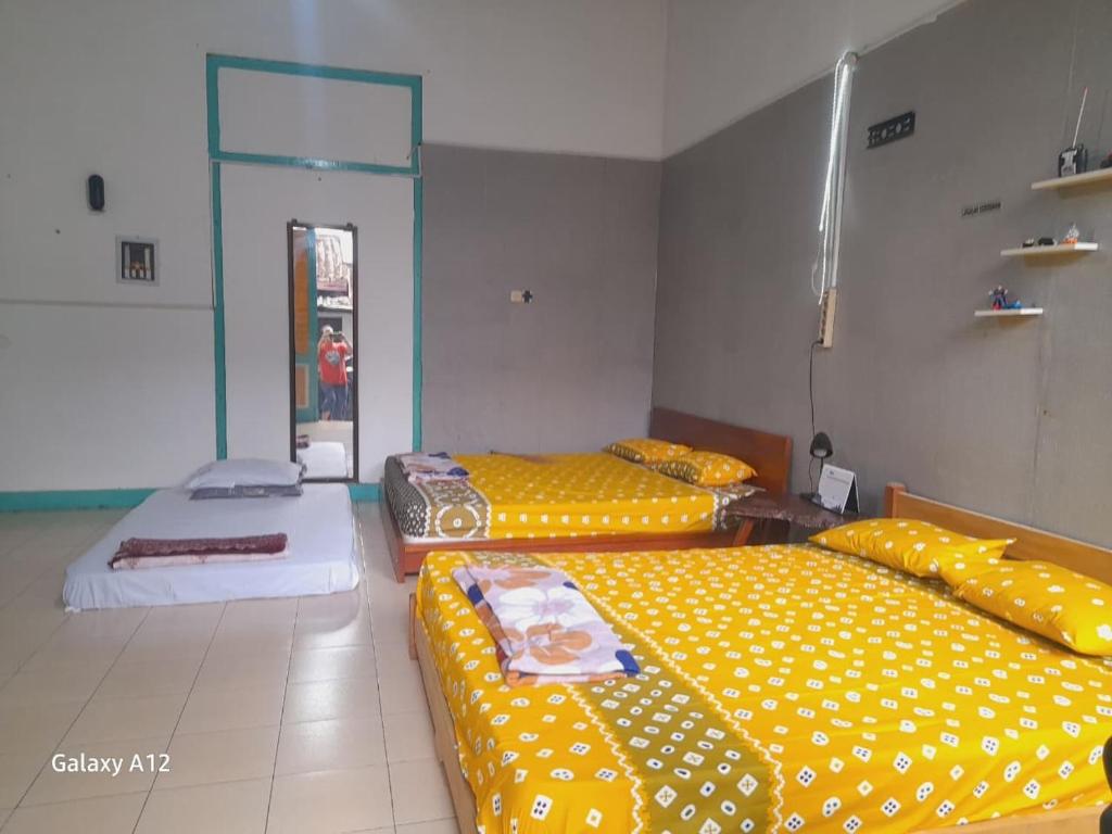 two beds in a room with yellow sheets at Ndalem Wongso in Yogyakarta