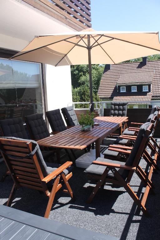 a wooden table and chairs with an umbrella on a patio at Ferienhaus Sauerzapf mit Saunabereich 16 Personen in Braunlage