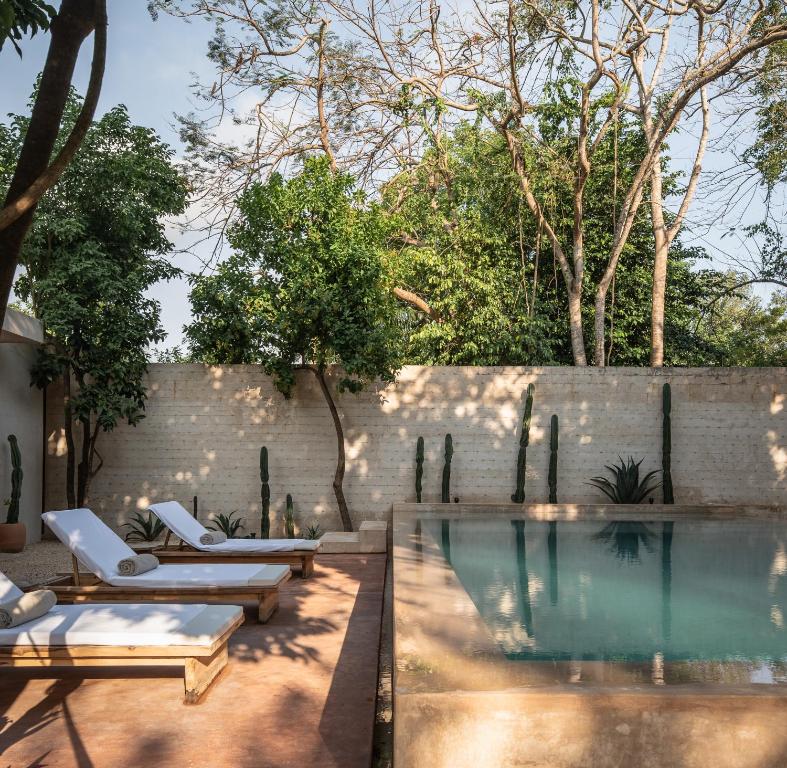 a swimming pool with lounge chairs and a wall at Casona los Cedros in Espita