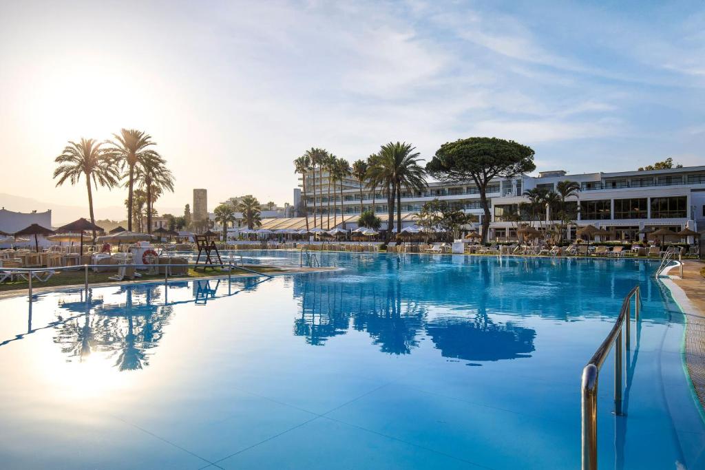 a large swimming pool with blue water and palm trees at SOL by Meliá Marbella Estepona - Atalaya Park in Estepona