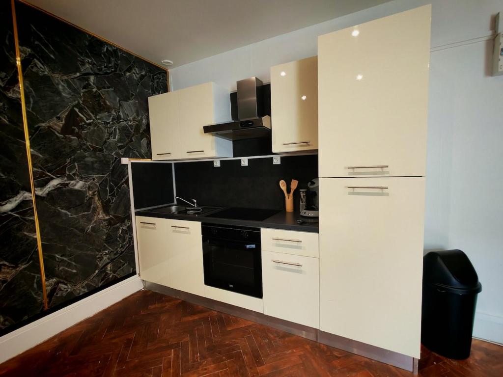 a kitchen with white cabinets and a black stove at Perle Centers in Dunkerque