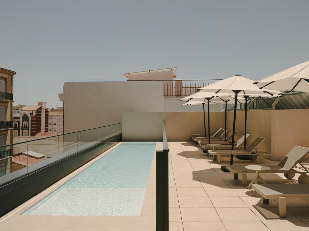 a swimming pool on top of a building with umbrellas at Sercotel Valencia Ruzafa in Valencia