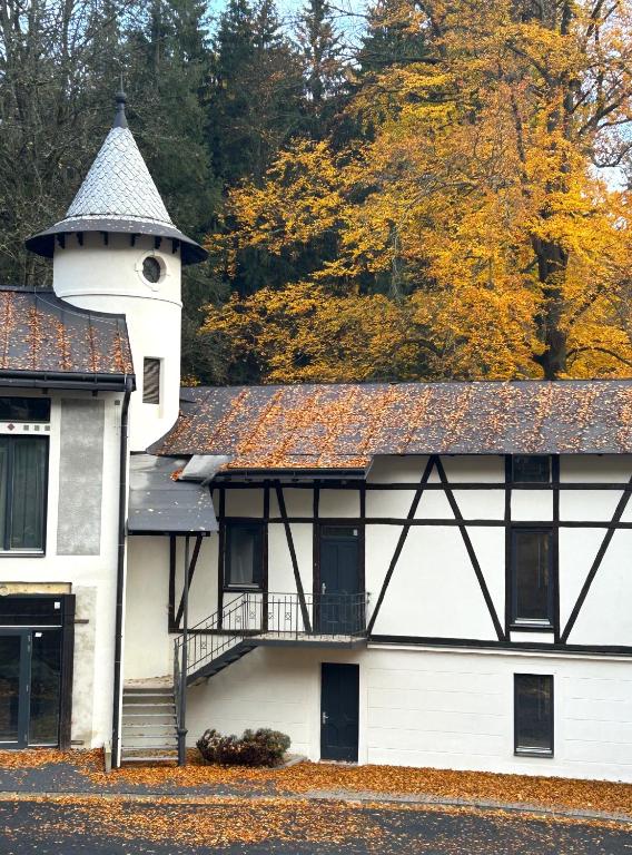 a white building with a tower and a balcony at Lesní Mlýn Depandance in Mariánské Lázně