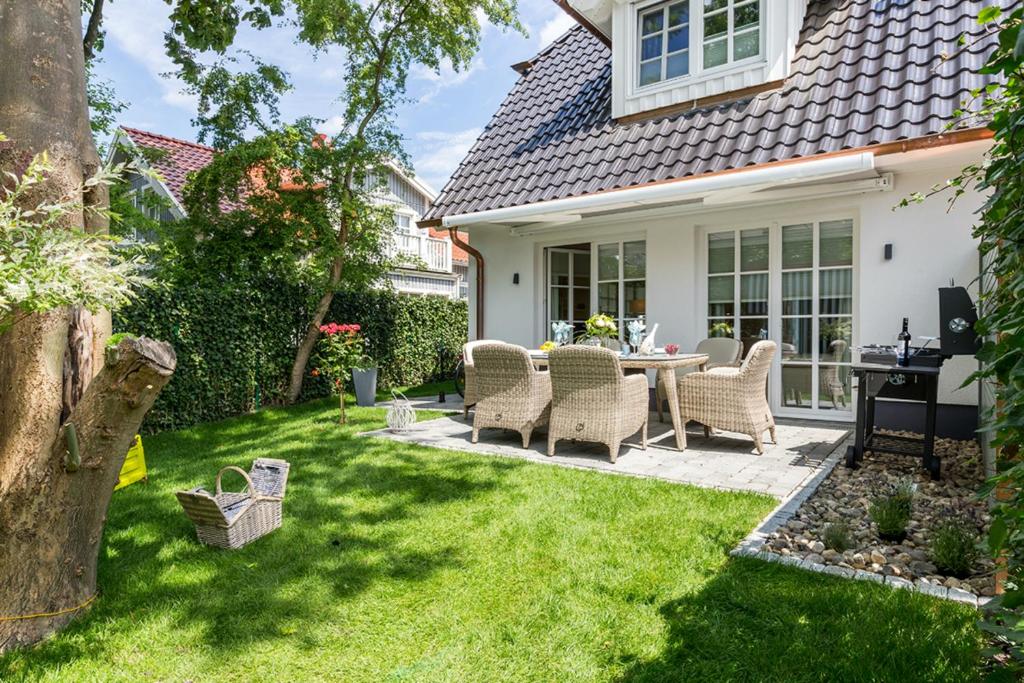 a patio with wicker chairs and a table in a yard at Ferienhäuser TraumZeit in Zingst