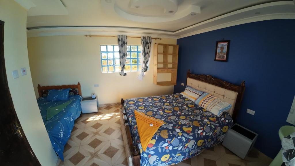 a bedroom with blue walls and a bed and a window at jc iten in Iten