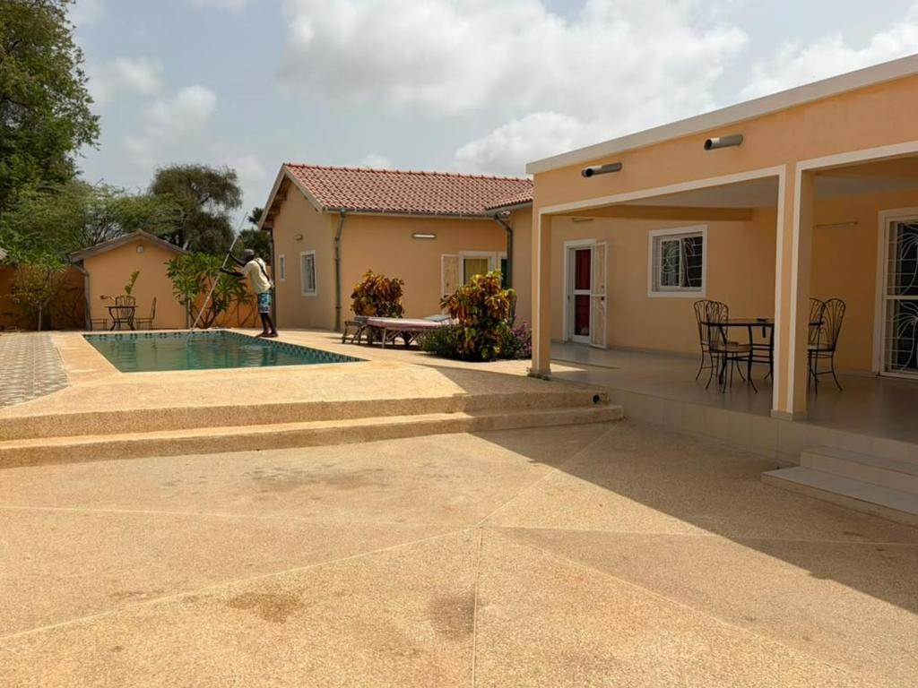 a person standing next to a house with a swimming pool at Le Clos Rivière in Ndangane
