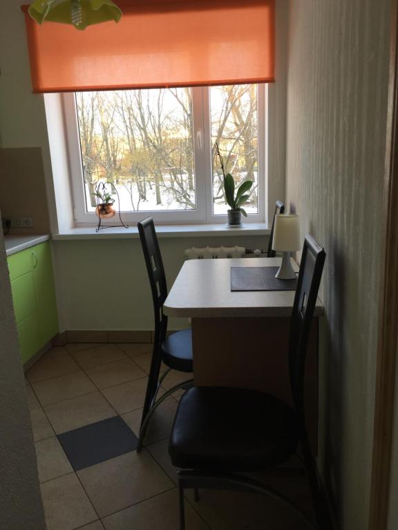 a desk with two chairs and a window with an orange curtain at Klaipedas 108 Street Apartment in Liepāja