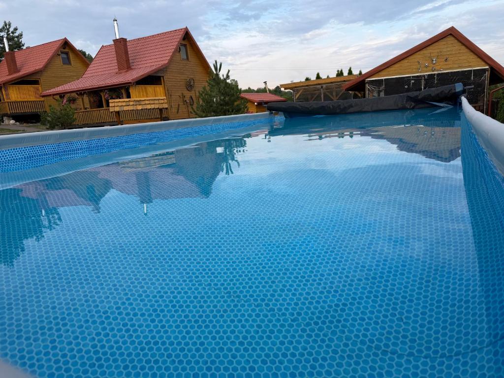 a swimming pool with blue water in front of houses at Luxdomki in Krasnobród