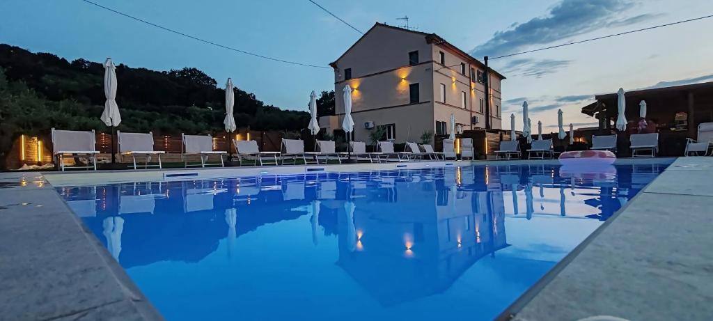 a swimming pool with chairs and a building in the background at QUEEN appartamenti e camere in Campofilone