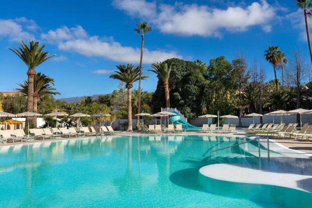 a large swimming pool with palm trees and a slide at SOL by Meliá Arona Tenerife in Los Cristianos