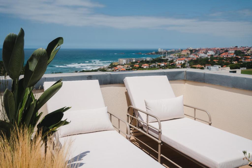 two chairs on a balcony with a view of the ocean at APPARTEMENT PISCINE TERRASSE 1 MIN PLAGE et GOLF in Bidart