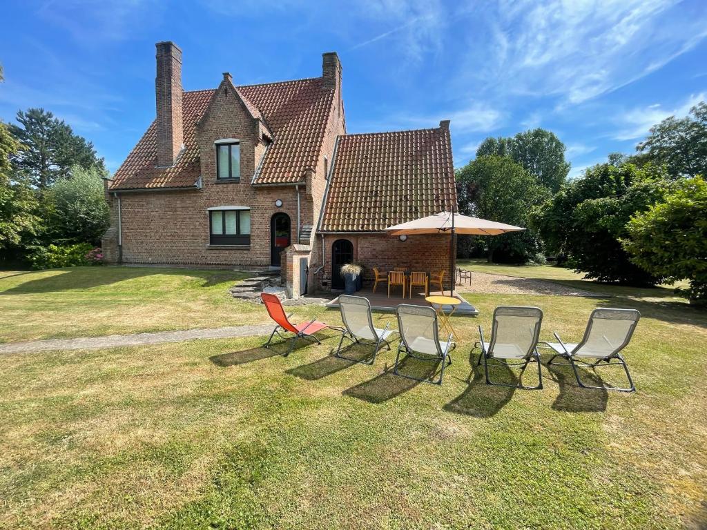 a group of chairs and an umbrella in front of a house at Le Logis - Charmante Maison Proche Plage in Rosendaël
