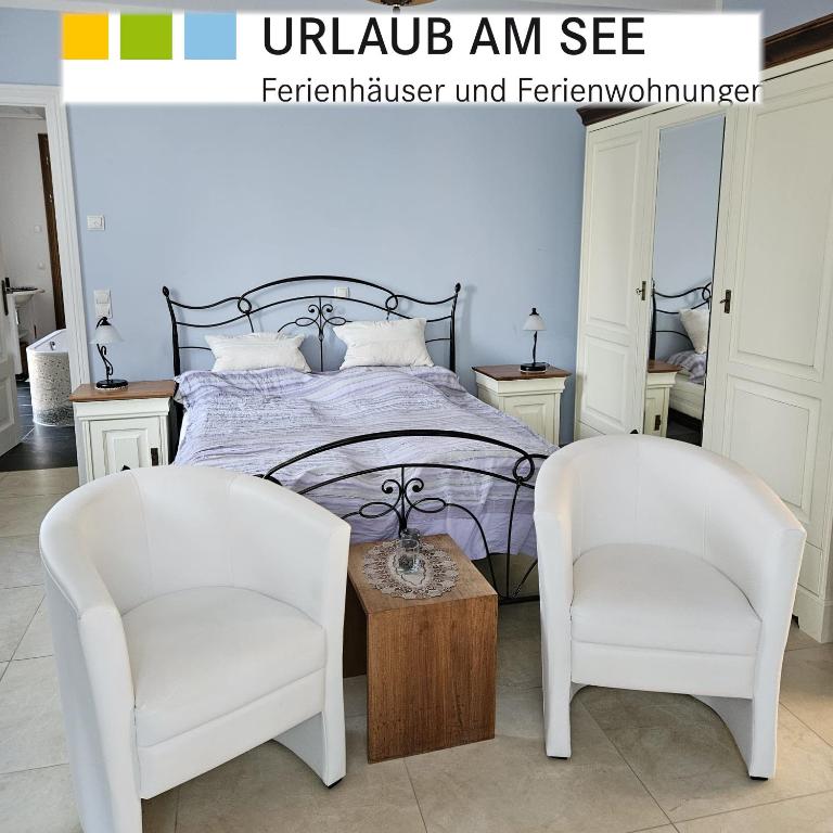 a bedroom with a bed and two white chairs at "Zweisam" am Scharmützelsee - Ferienwohnung mit mediterranem Charme in Diensdorf-Radlow