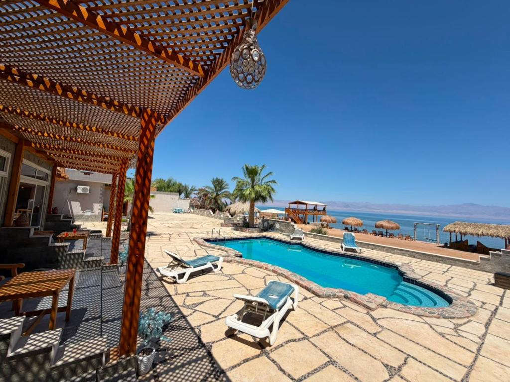 a swimming pool with two lounge chairs and the ocean at Bonanza beach camp in Nuweiba