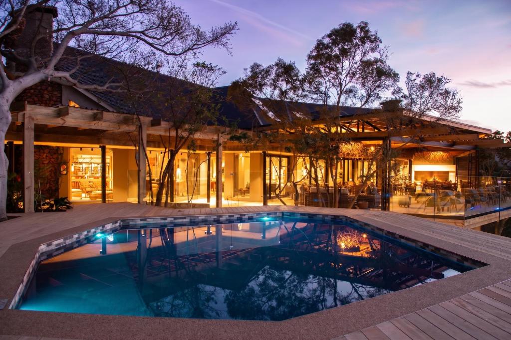 a swimming pool in front of a house at Botlierskop Tented Lodge in Reebok