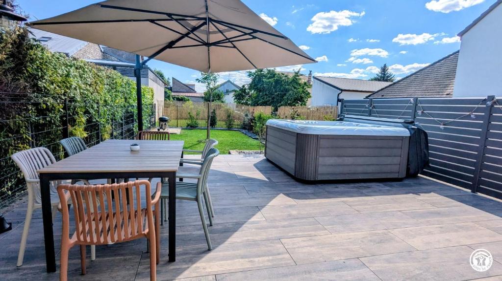 a patio with a table and a hot tub at Le Petit Vigneron in Nuits-Saint-Georges