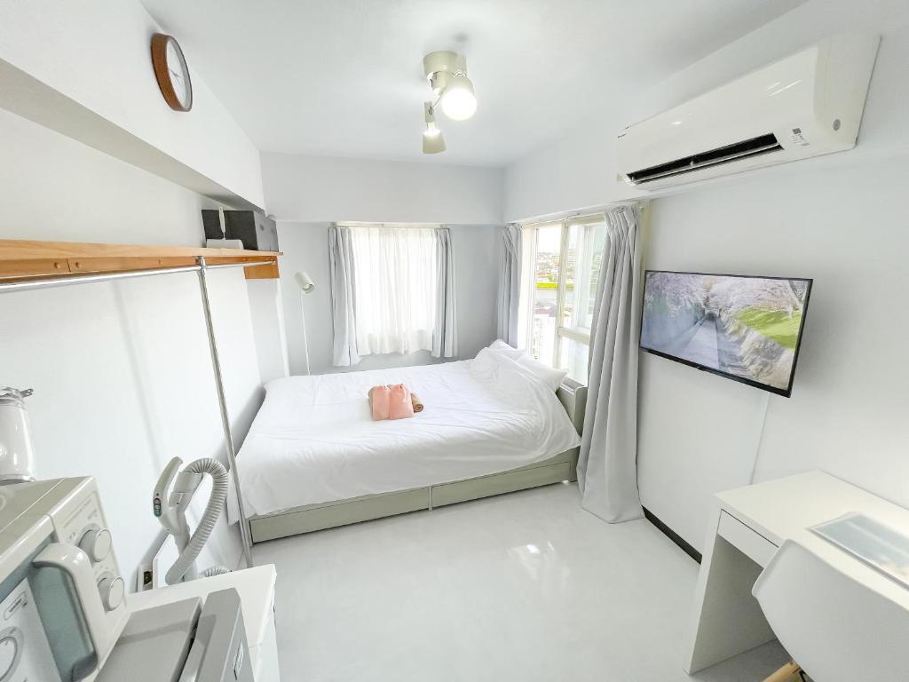 a small white bedroom with a bed and a tv at Kameari 1111 - 11F Newly Renovated High Floor City View 2min to Mall 5min to Station Disney Access in Tokyo