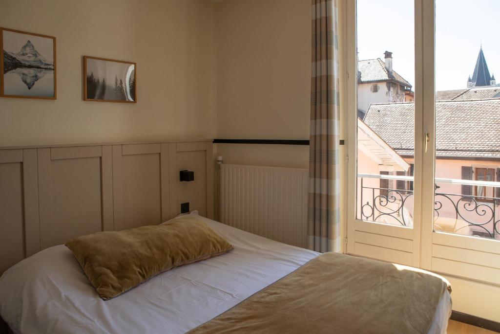 a bedroom with a bed and a large window at Hôtel du Nord in Annecy