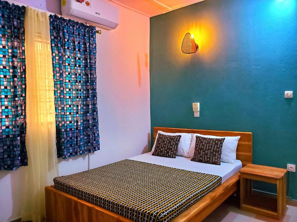 a bedroom with a bed with a blue wall at Maison fleurie Ouidah in Ouidah
