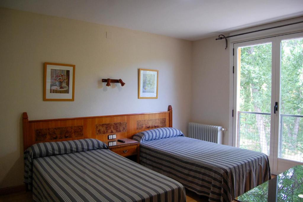 een slaapkamer met twee bedden en een raam bij Hotel El Tablazo in Villalba de la Sierra
