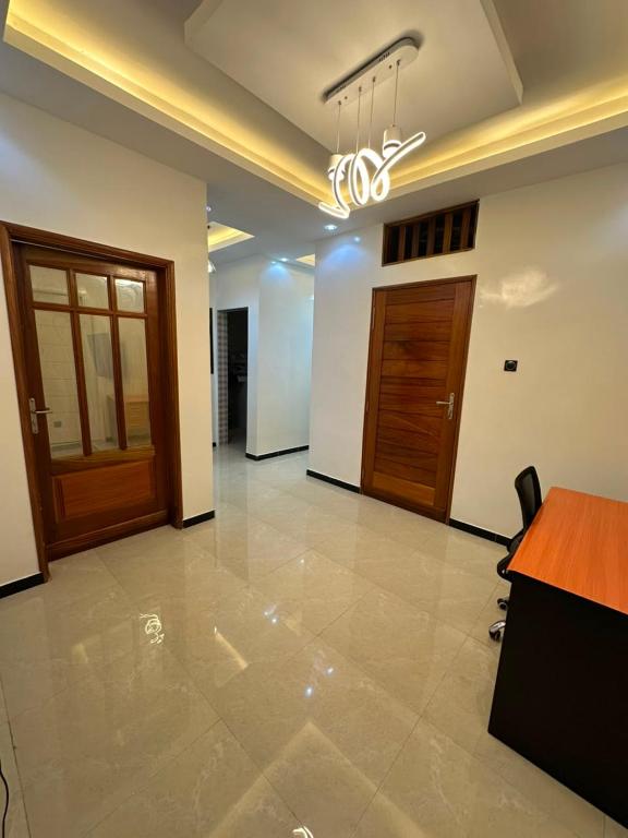 an empty lobby with a chandelier and wooden doors at Appartement confort keur massar in Rufisque