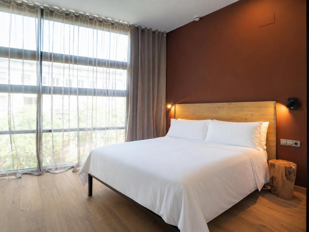 a bedroom with a white bed and a large window at Aspasios Born in Barcelona